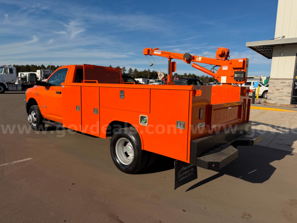 Orange Ram 3500 utility/service truck back view with multiple storage compartments and a mounted boom crane.