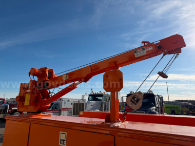 Truck-mounted crane on a Ram 3500 utility body showing orange crane arm and hydraulic components.