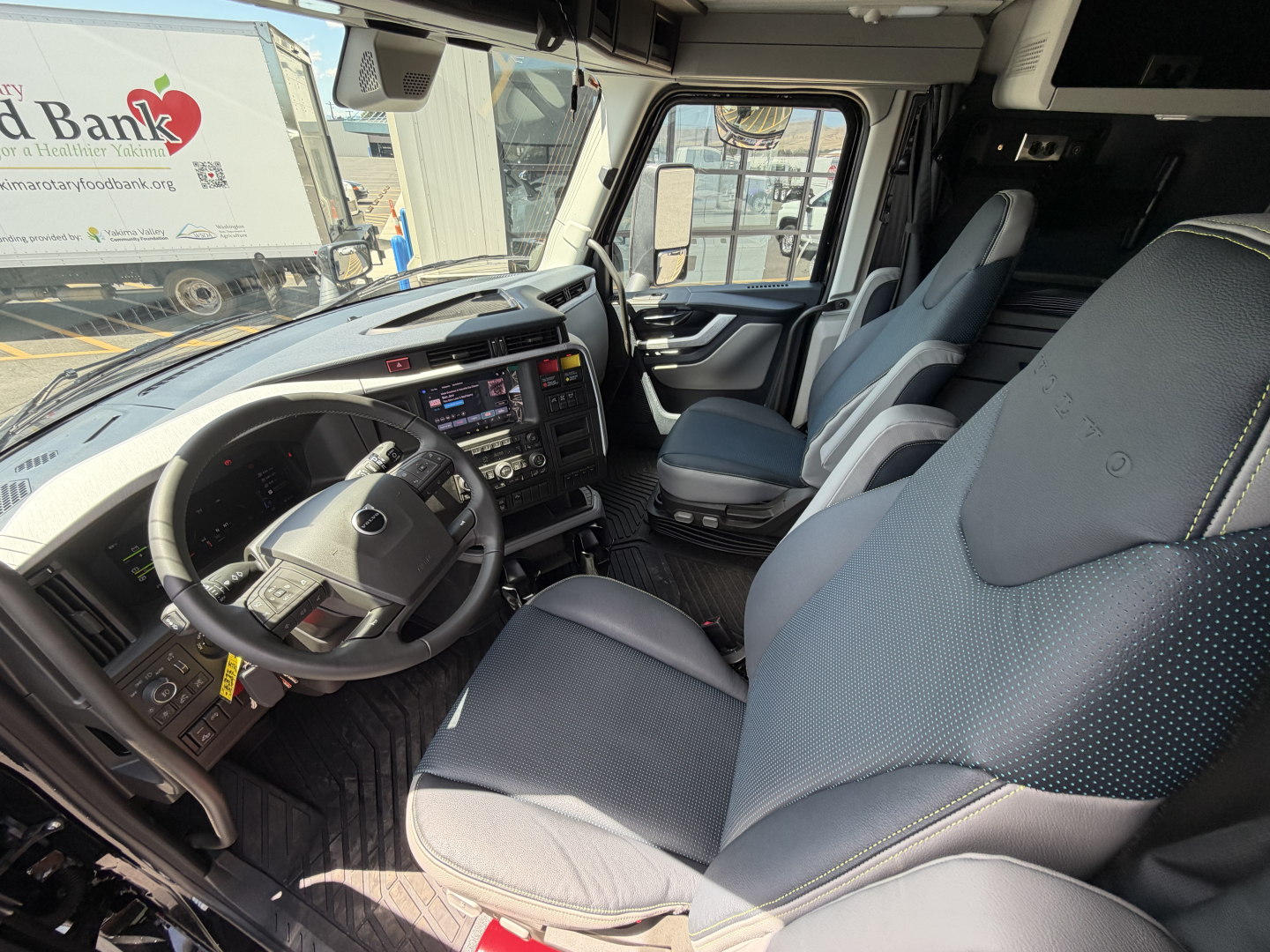 Volvo VNL interior cab view showing steering wheel, dashboard, and front seats. Visible text on dashboard includes digital gauges and control panels.
