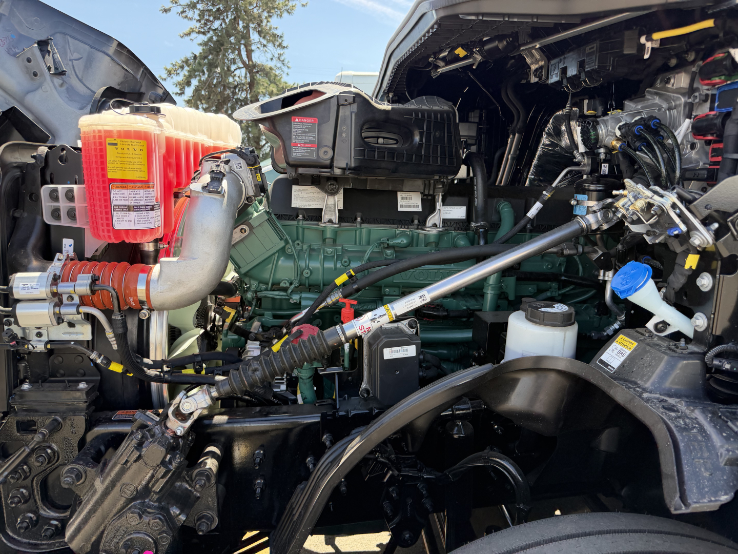Volvo VNL64T860 engine bay showing diesel engine, coolant reservoir, hoses, and wiring harness.