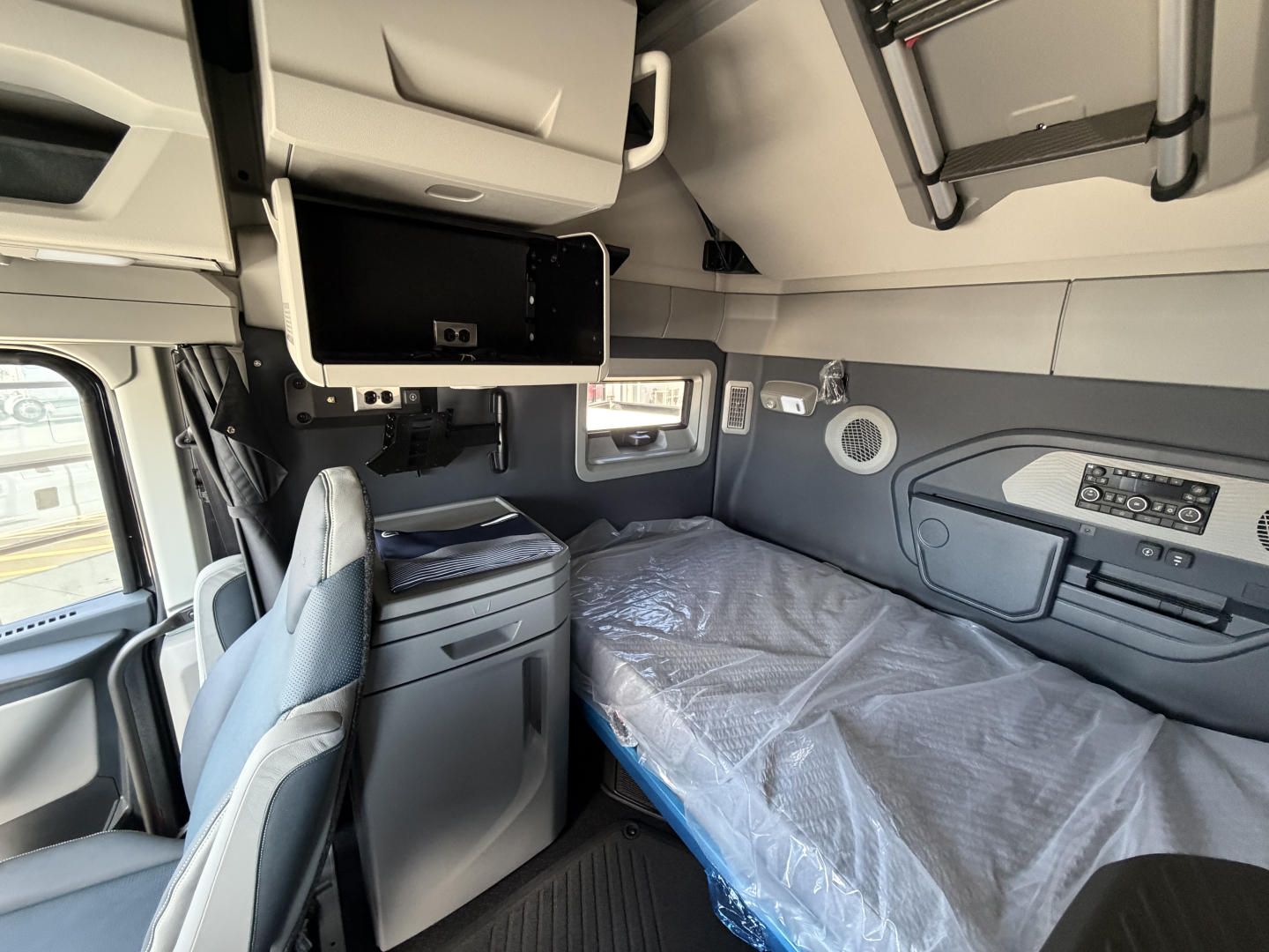Volvo VNL64T860 sleeper cab interior with bunk bed, overhead storage, and control panel.