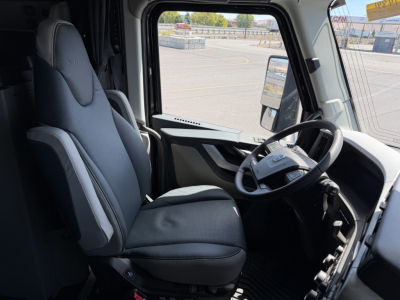 Cab interior of a Volvo VNL tractor showing driver seat and steering wheel, dashboard, and window view.