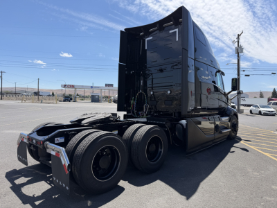 New 2027 Volvo VNL64T860 conventional sleeper truck in black, rear three-axle configuration with exposed fifth wheel and dual rear tires.