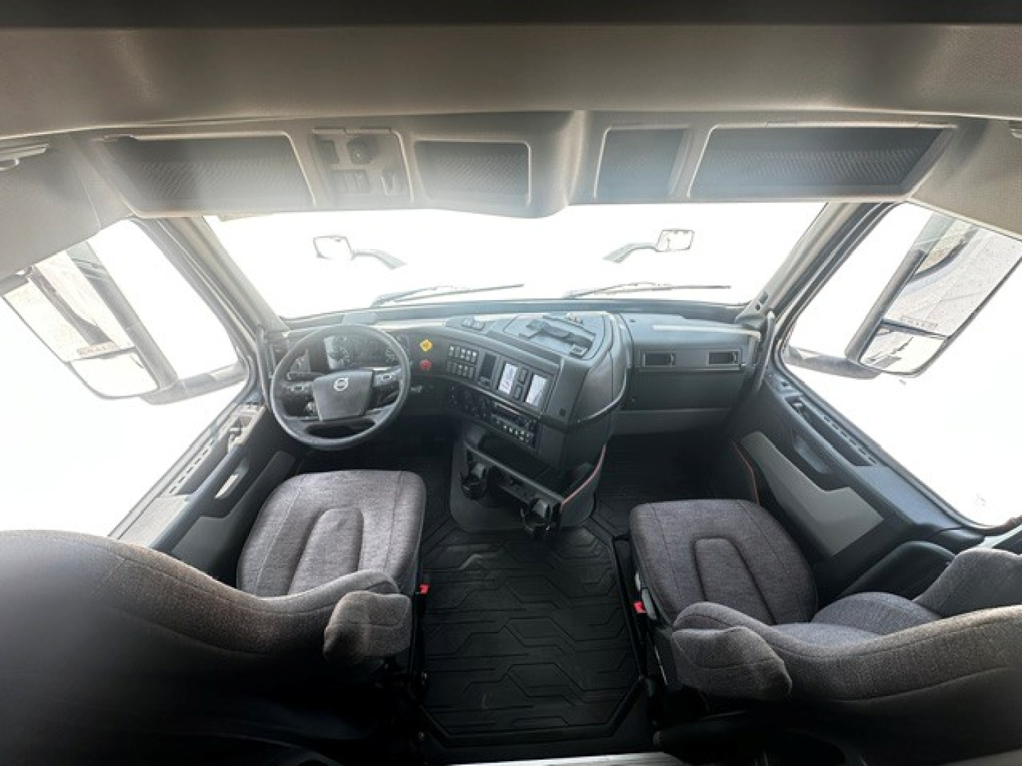 Truck cab interior of a 2021 Volvo VNL64T740 showing steering wheel and dashboard with two front seats.