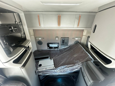 Volvo VNL64T740 sleeper cab interior showing dashboard area, storage cabinets, and passenger seat covered in plastic.