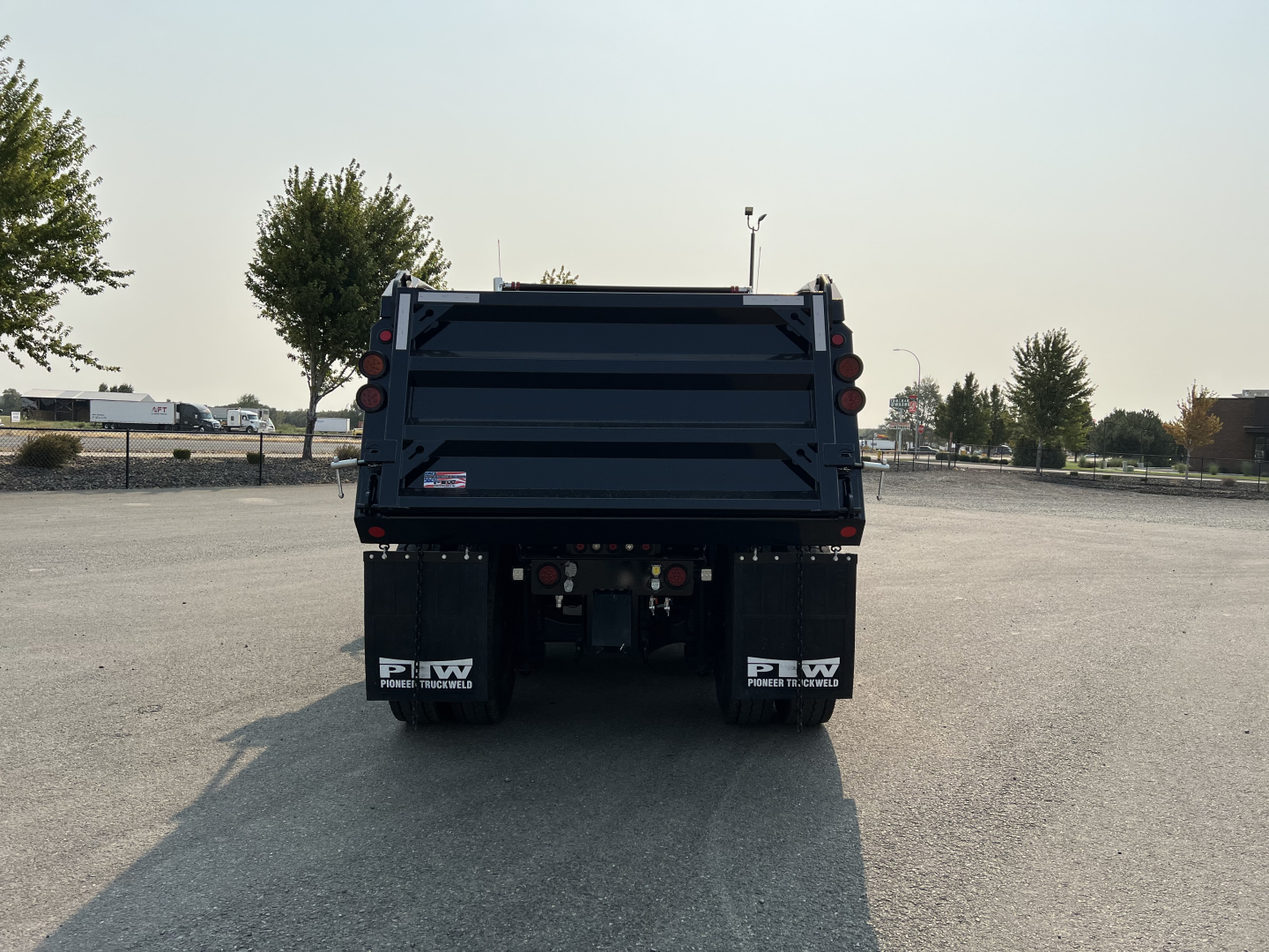 Rear view of a new 2027 Mack GR84F dump truck showing the truck bed and mud flaps with PW North America logos visible.