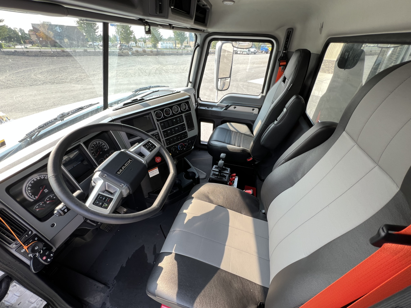 Cab interior of a 2027 Mack GR84F dump truck showing steering wheel dashboard and front seats with gray upholstery