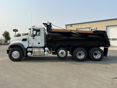 Dump truck side profile showing a white Mack GR84F cab and a black dump bed with six wheels, VIN 1M2GR4NC4VM010024, stock 73249, new truck.