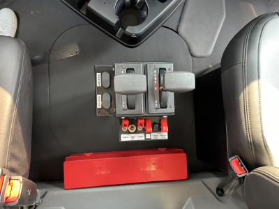 Mack GR84F truck interior center console with two joystick controls and red storage bin beneath. Visible labels on levers and panels.