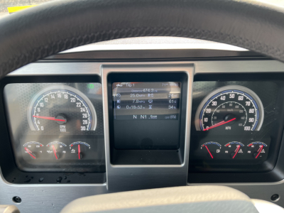 Dashboard view of a Mack GR84F truck showing analog gauges and a central display screen with trip data.