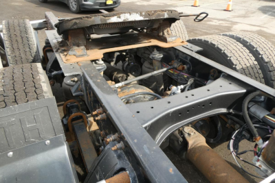 Kenworth T660 chassis showing engine bay and drivetrain components with frame rails and suspension; visible are hoses, wiring, and rust-toned exhaust area.