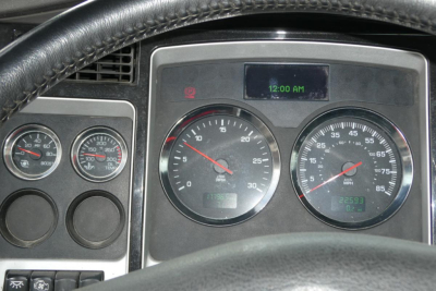 Dash gauge cluster of a Kenworth T660 showing speedometer, tachometer, and digital clock/display with steering wheel in foreground.