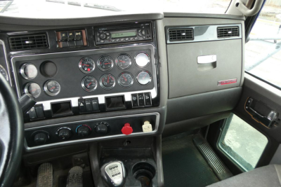 Kenworth T660 truck interior dashboard showing instrument gauges, switches, and gear shifter in cab.