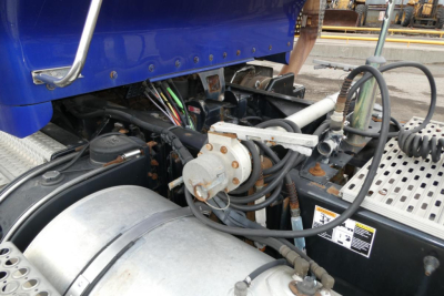 Kenworth T660 engine bay showing air compressor and air lines with wiring harness and chrome air intake tube.