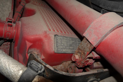 Kenworth T660 engine bay with identification placard and red components; visible plate shows model/engine info.