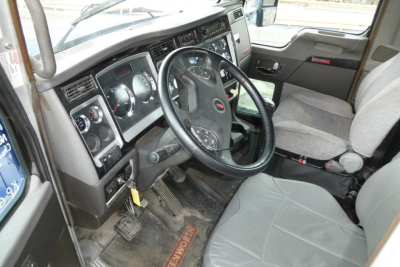 Interior of 2013 Kenworth T660 driver area showing steering wheel, dashboard gauges, and driver's seat.