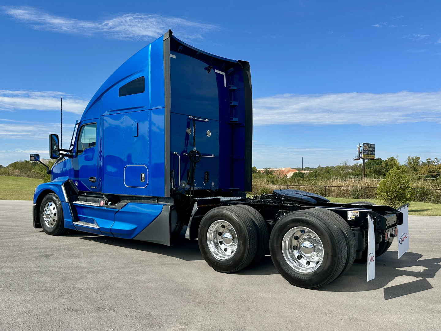 Blue 2023 Kenworth T680 tractor in side view showing sleeper cab and dual rear axles with chrome wheels.