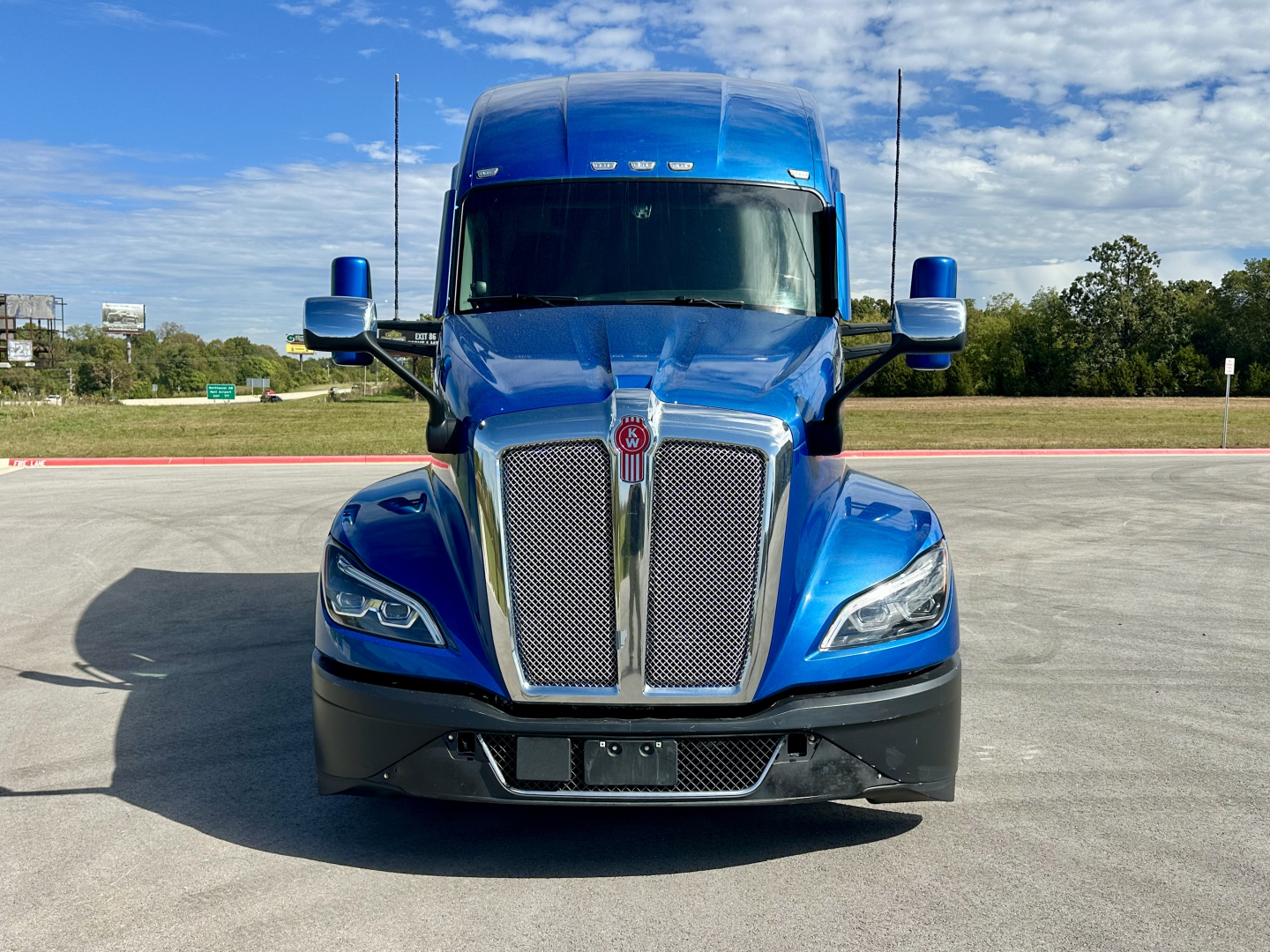 Kenworth T680 truck front view showing blue cab with chrome grille and headlights.