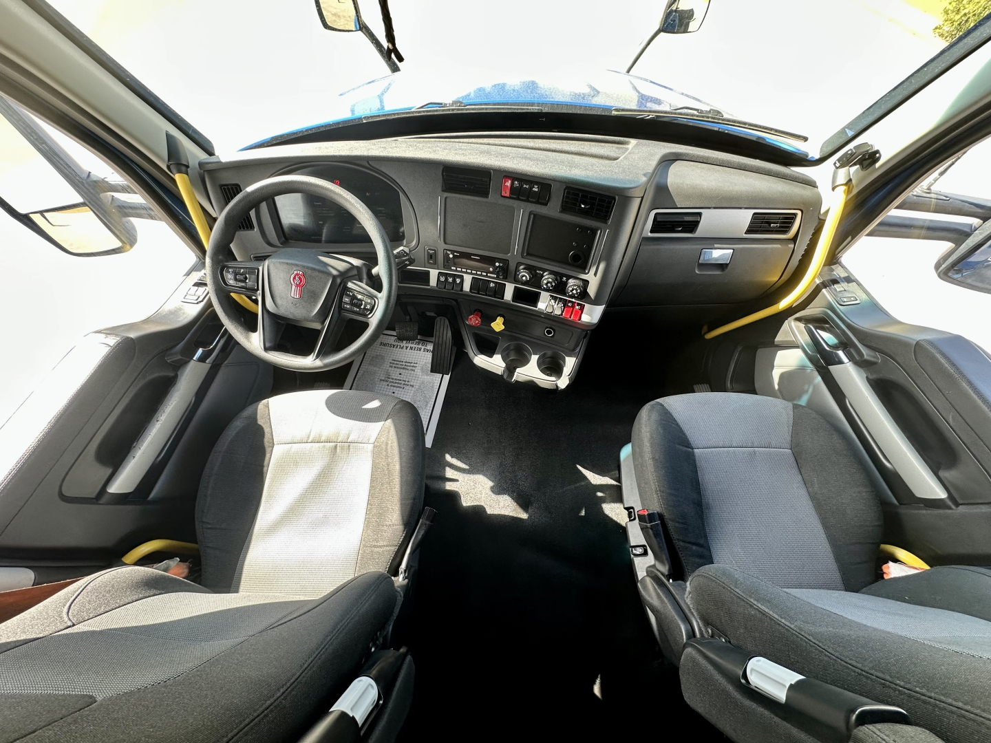 Kenworth T680 truck interior dashboard view with steering wheel, center console, and driver and passenger seats.