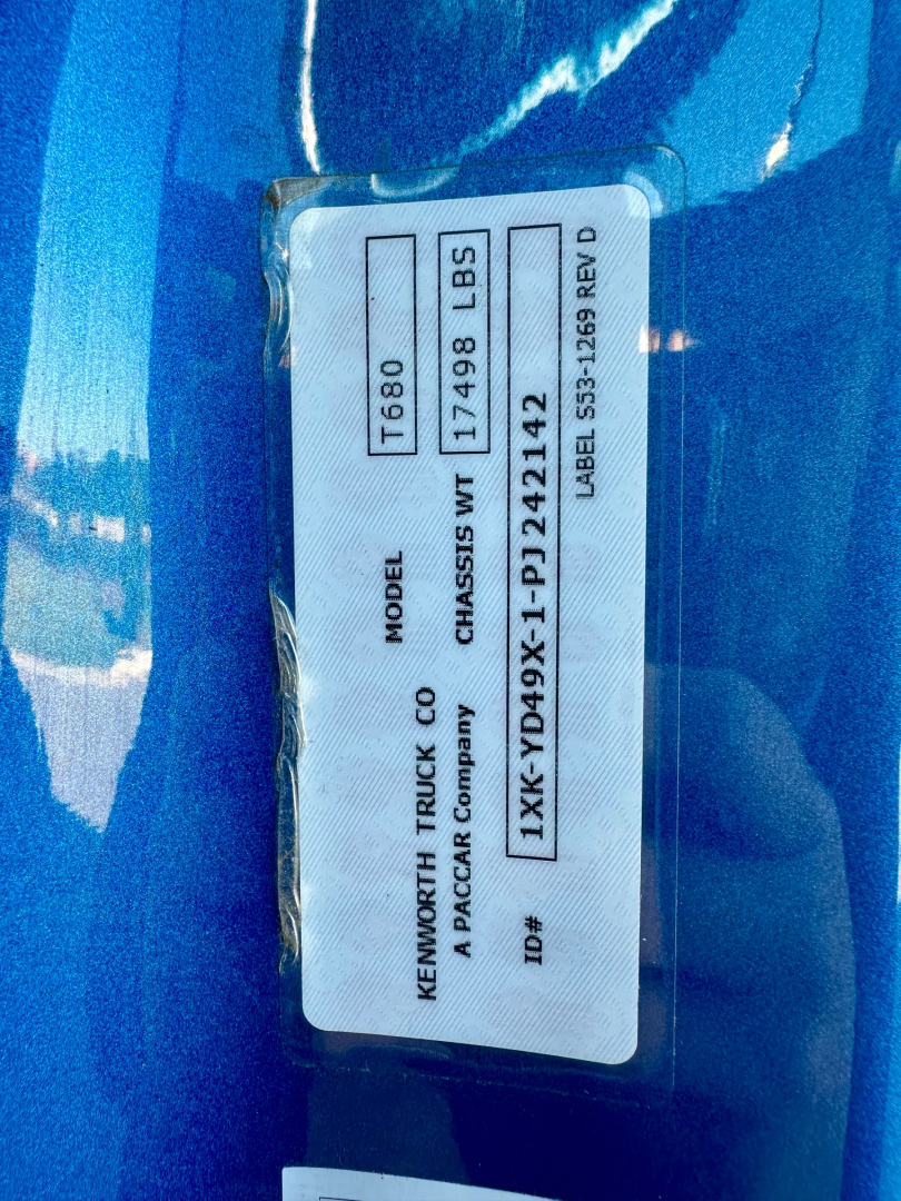 Vehicle ID label on Kenworth T680 door showing model T680, chassis WT 17498 LBS, 1XKYD49X1PJ242142 VIN, 0633551 stock, Rev D, PACCAR badge.
