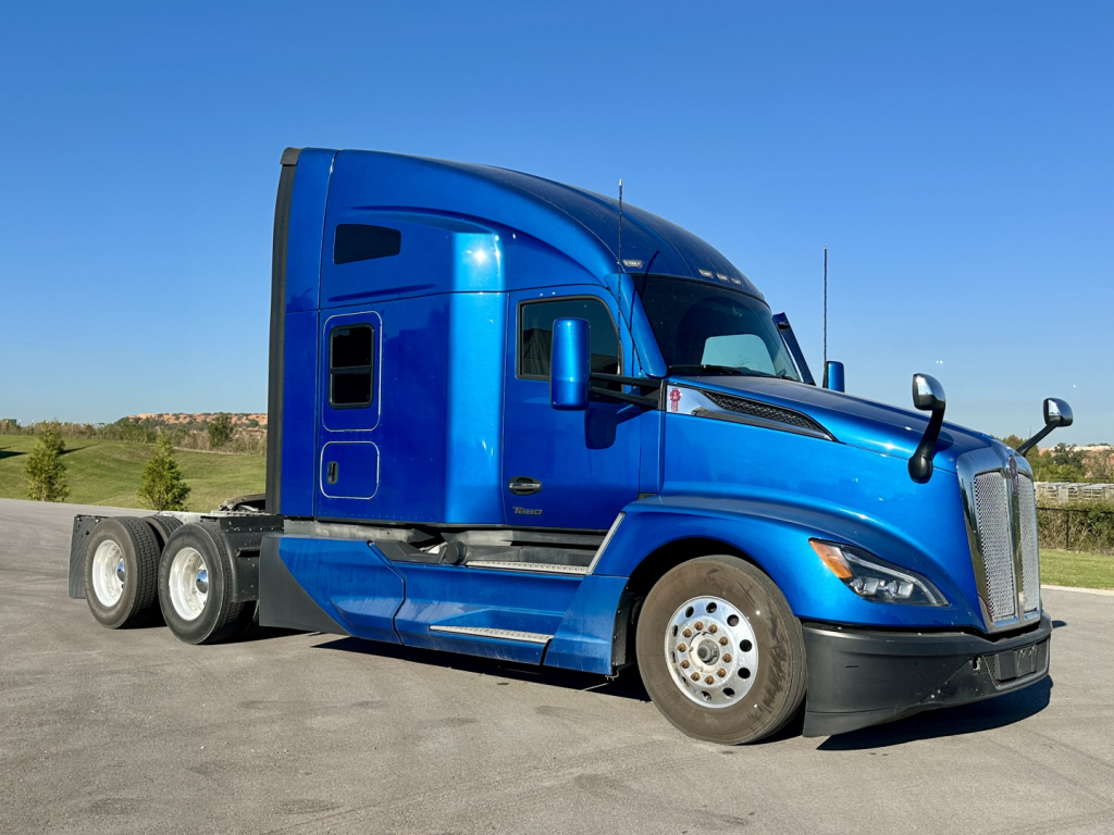 Blue 2023 Kenworth T680 conventional sleeper truck side view with three-axle rear, VIN 1XKYD49X1PJ242142, stock 0633551.