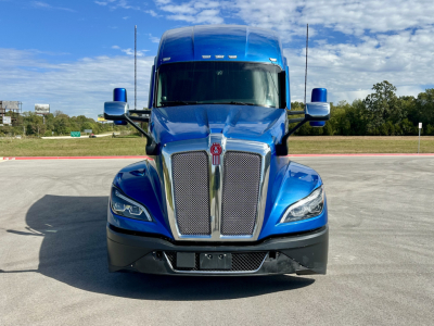 Kenworth T680 truck front view showing blue cab with chrome grille and headlights.