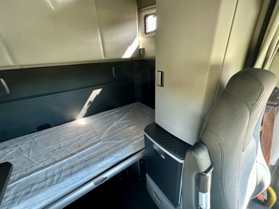 Kenworth T680 sleeper cab interior with a single bed and storage area visible.