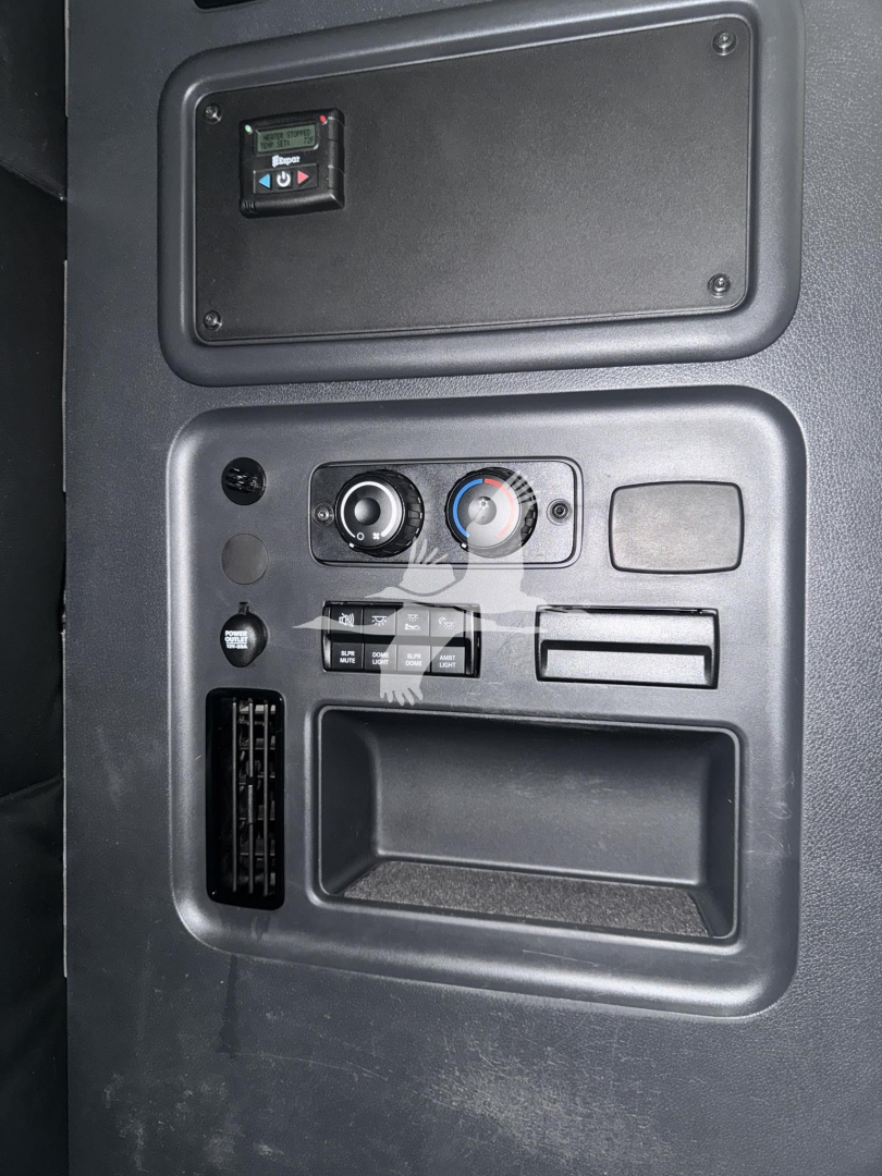 Dashboard area of a Freightliner Cascadia sleeper showing climate controls, storage pocket, USB/Cig lighter area, and vent.