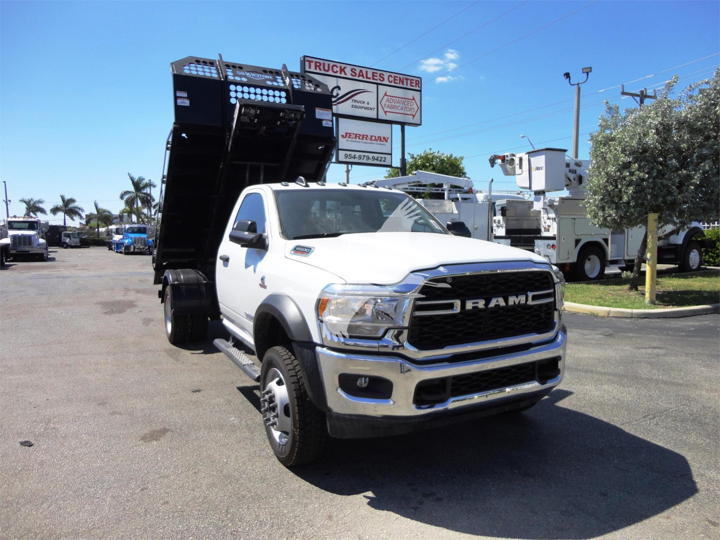 Ram 5500HD dump truck cab showing front grille with RAM emblem, raised black dump bed, highway in background.