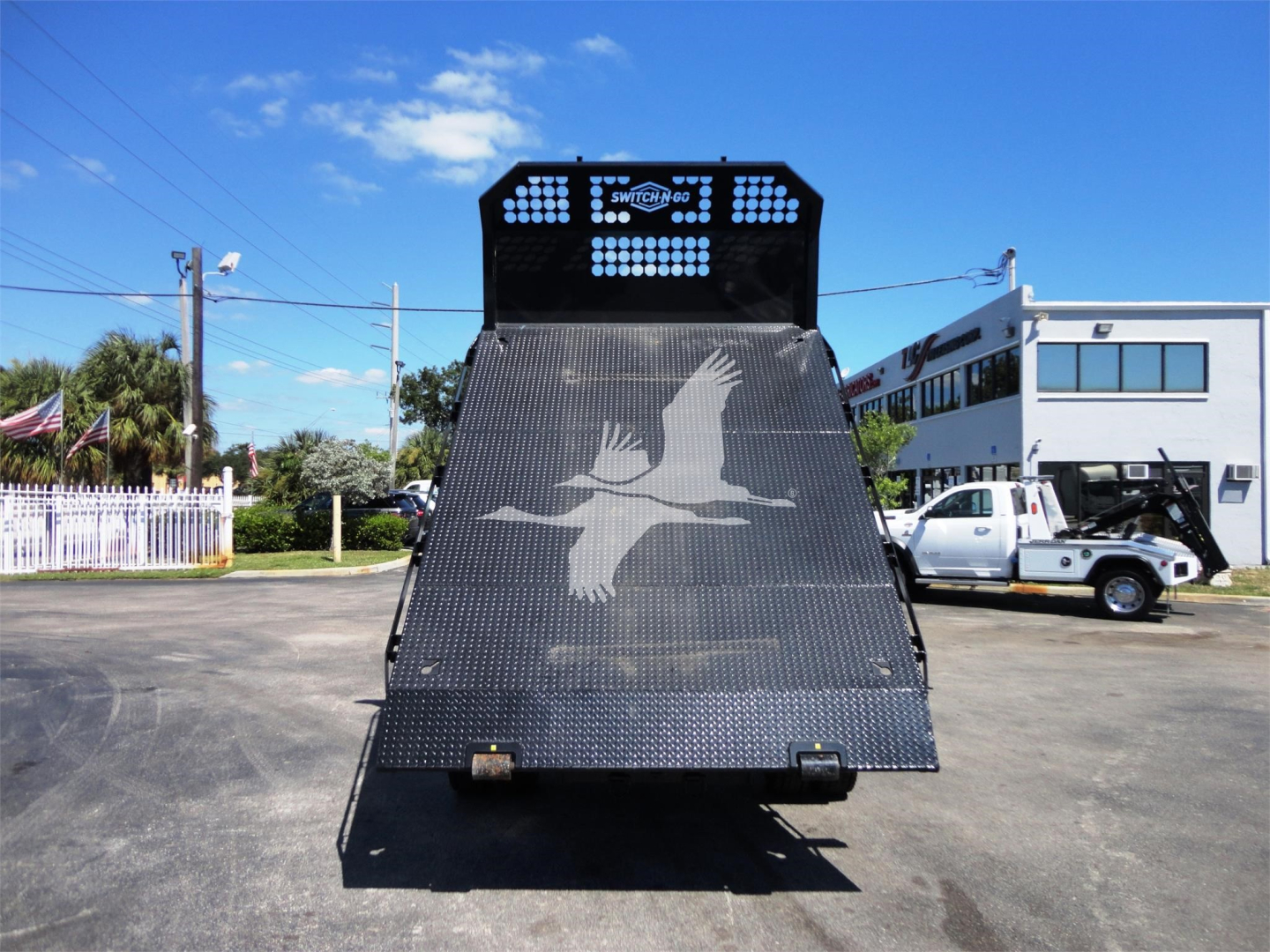 Ram 5500 HD hooklift truck rear with large diamond plate bed and spreader wing, truck yard in background