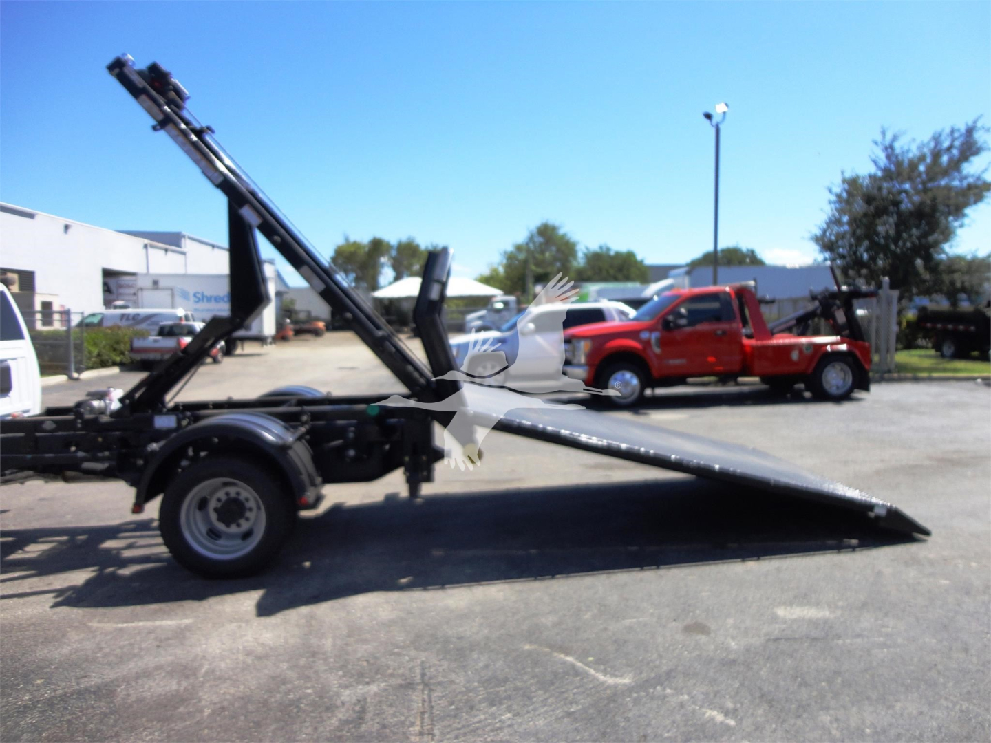Ram 5500 HD hooklift truck trailer with raised bed and hydraulic system showing side profile and front wheel