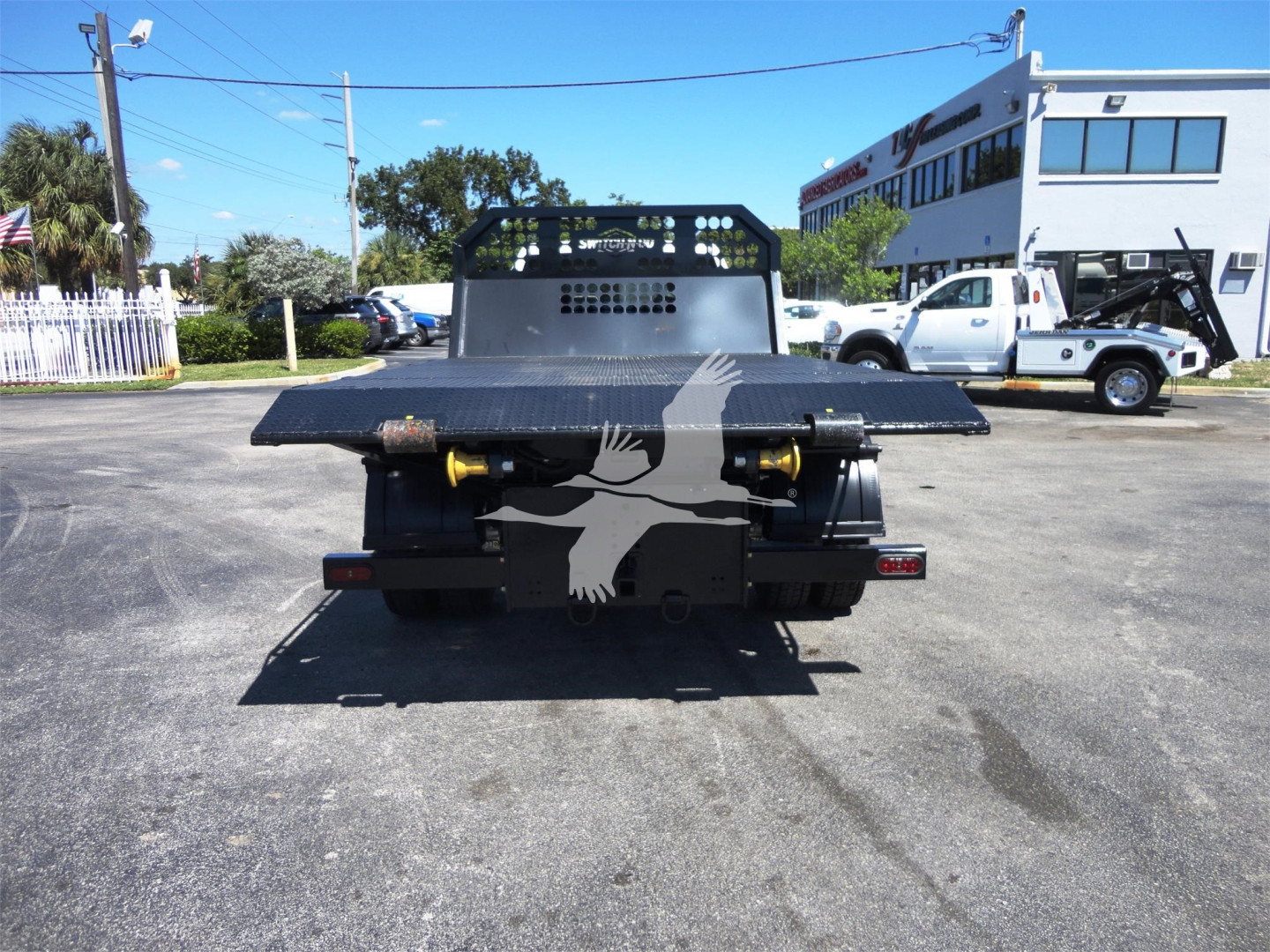 Ram 5500HD hooklift truck rear view showing flatbed with hydraulic hooks and bumper lights.