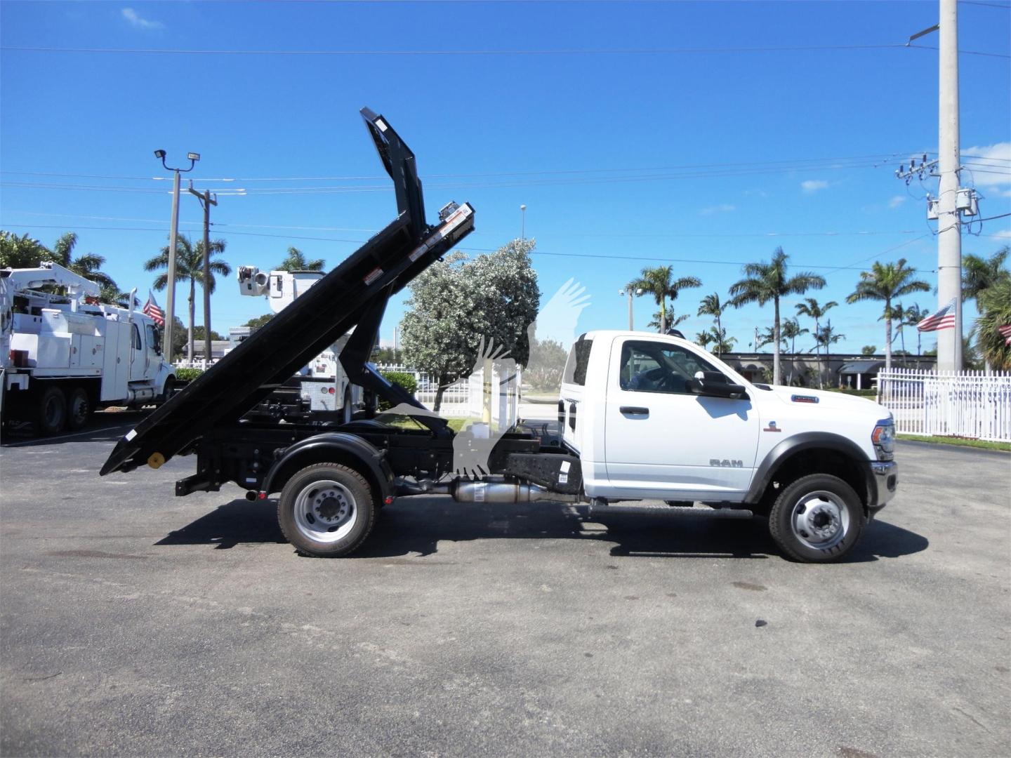 Ram 5500HD hooklift truck side view with raised bed tilting mechanism and white cab.