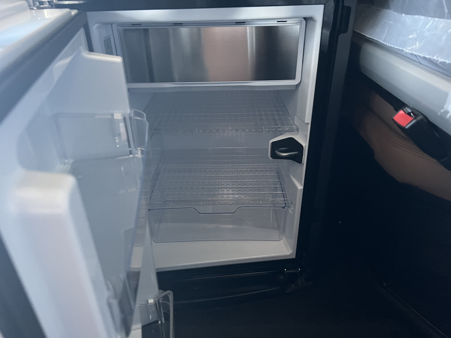 Refrigerator/freezer compartment of a new Mack PR64T76H sleeper truck showing empty shelves and interior light.