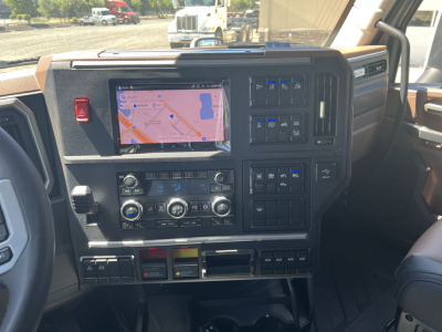 Dashboard of a 2027 Mack PR64T76H truck with a touchscreen navigation display, multiple control panels, climate controls, and various switches.