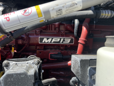 Engine bay of a 2027 Mack PR64T76H showing the MP13 engine cover and surrounding hoses and components.