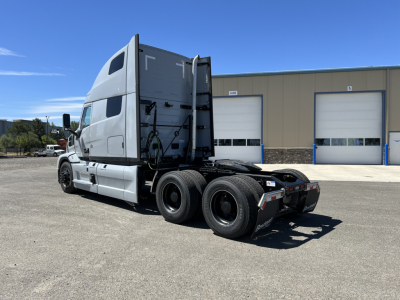 Truck cab and rear chassis of a new Mack PR64T76H tractor, side view showing sleeper cab and dual rear axles.