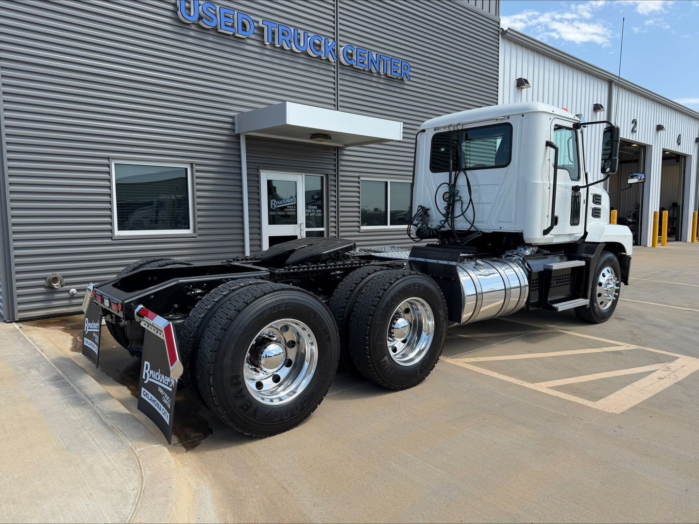 Tractor unit view of a 2020 Mack Anthem daycab showing dual rear axles and chrome wheels in a used truck lot.