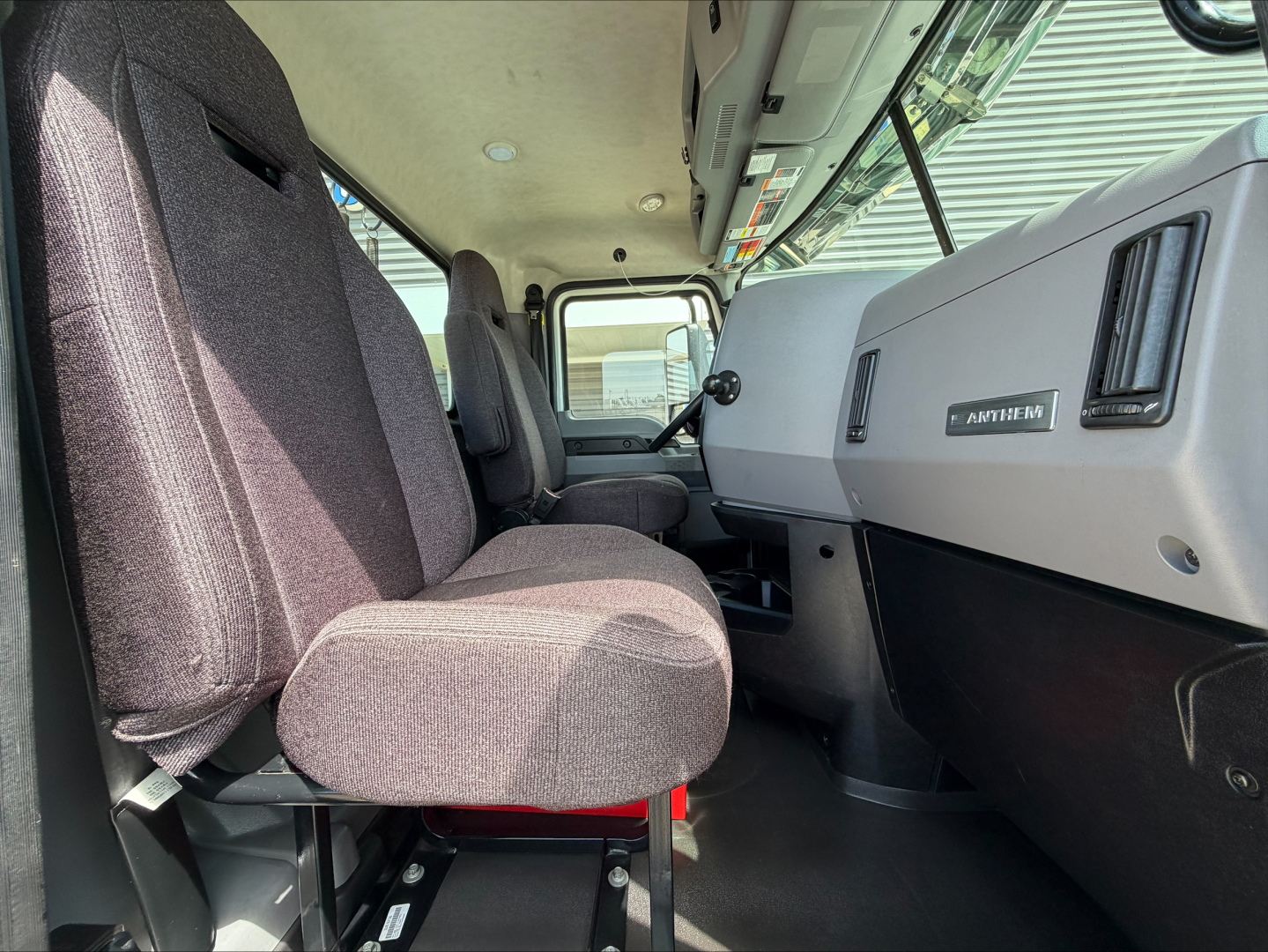 Cab interior of a 2020 Mack Anthem truck showing driver seat, passenger seat, steering wheel, dashboard with Mack logo, and window view.