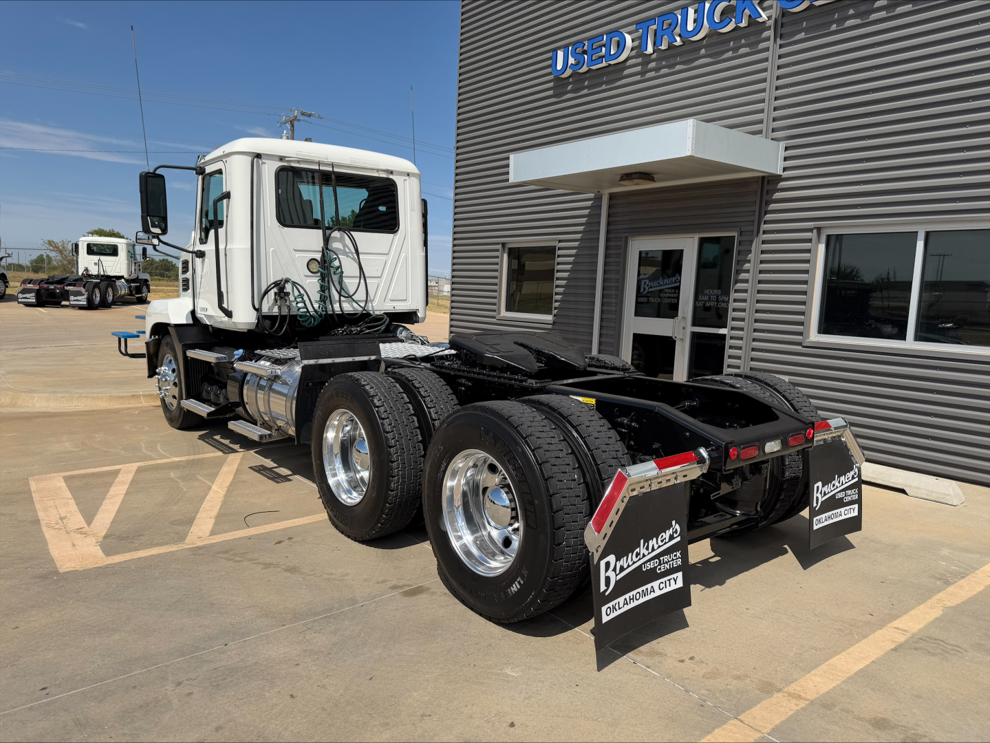 Truck chassis and cab of a 2020 Mack Anthem conventional daycab, white cab, dual rear axles, visible fuel tanks and chrome wheels, parked outside a used truck dealer.