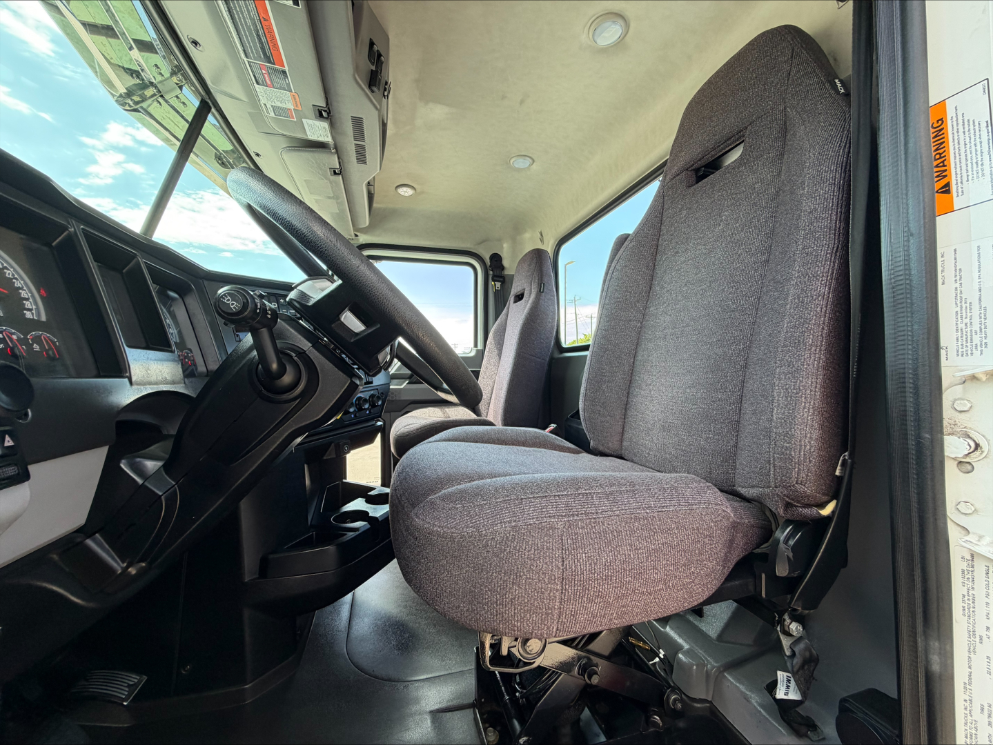 Interior of a 2020 Mack Anthem daycab showing driver and passenger seats, steering wheel, and dashboard view from open door.
