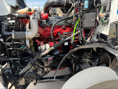 Mack Anthem engine bay showing red diesel engine, hoses, wiring, and front suspension components.
