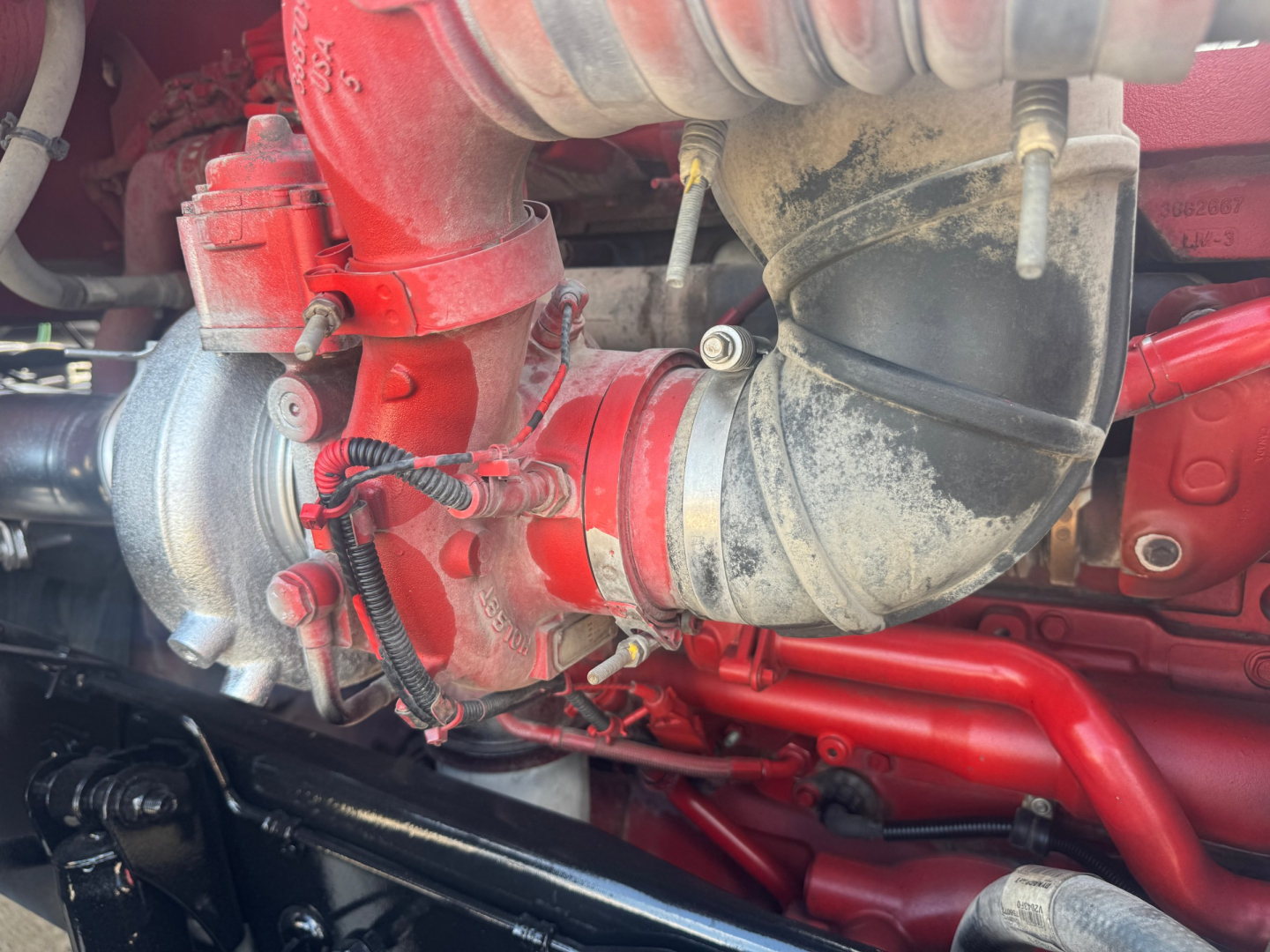 Peterbilt 579 engine bay showing red turbocharger and intercooler piping with hoses and engine components.