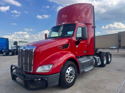 Peterbilt 579 conventional daycab tractor in red, side view showing grille, high sleeper cab, and dual rear axles.