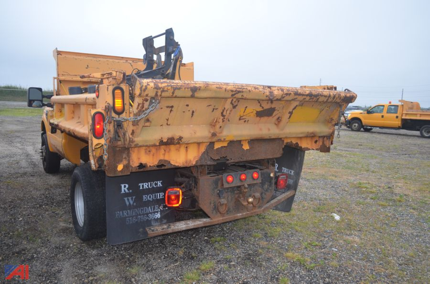 Rear view of a 2009 Ford F350 Super Duty dump truck showing chipped yellow paint and plow mounting apparatus.