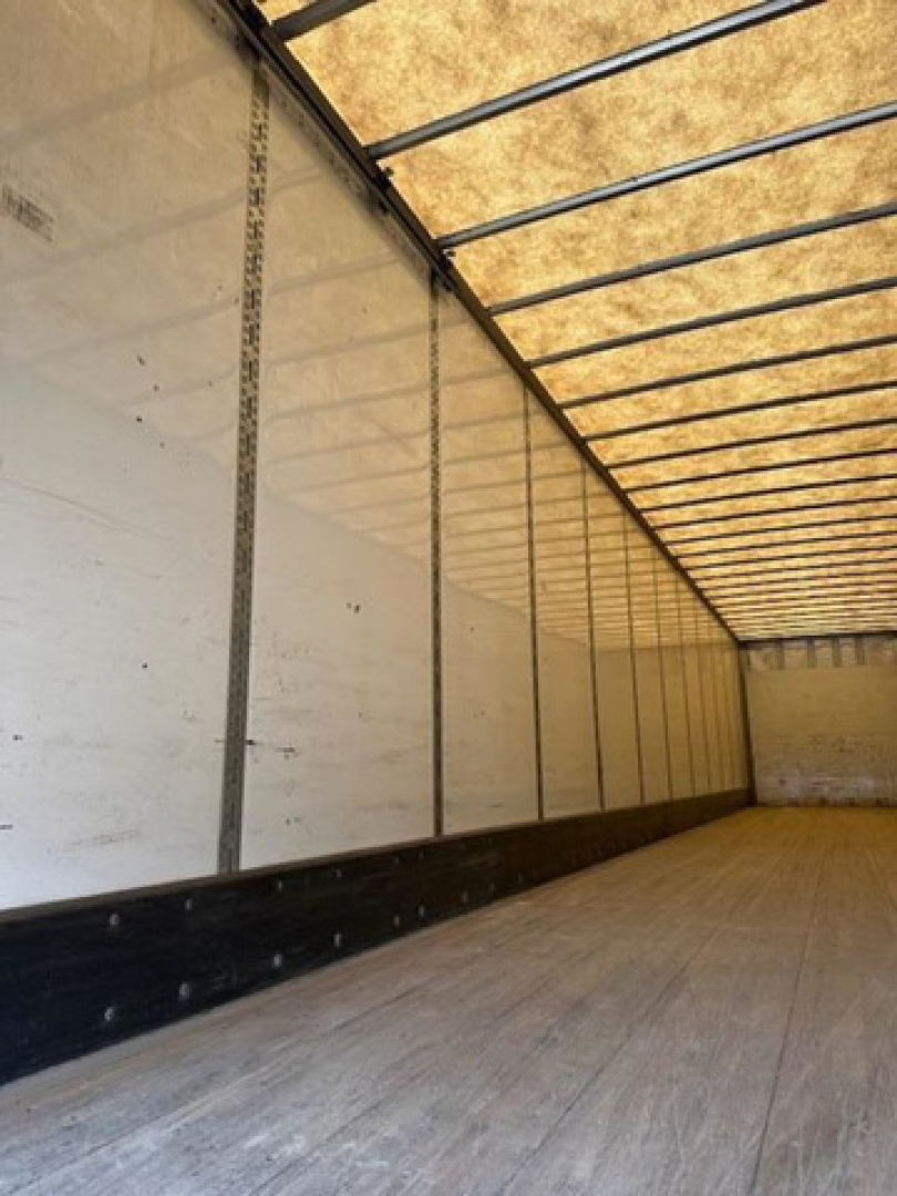 Trailer interior showing empty Wabash van box with vertical rails and plywood floor.
