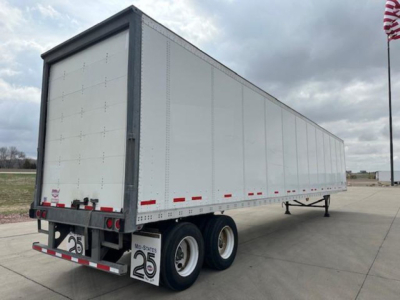 Trailer side view showing a long white Wabash van trailer with dual rear wheels and rear bumper safety lights.