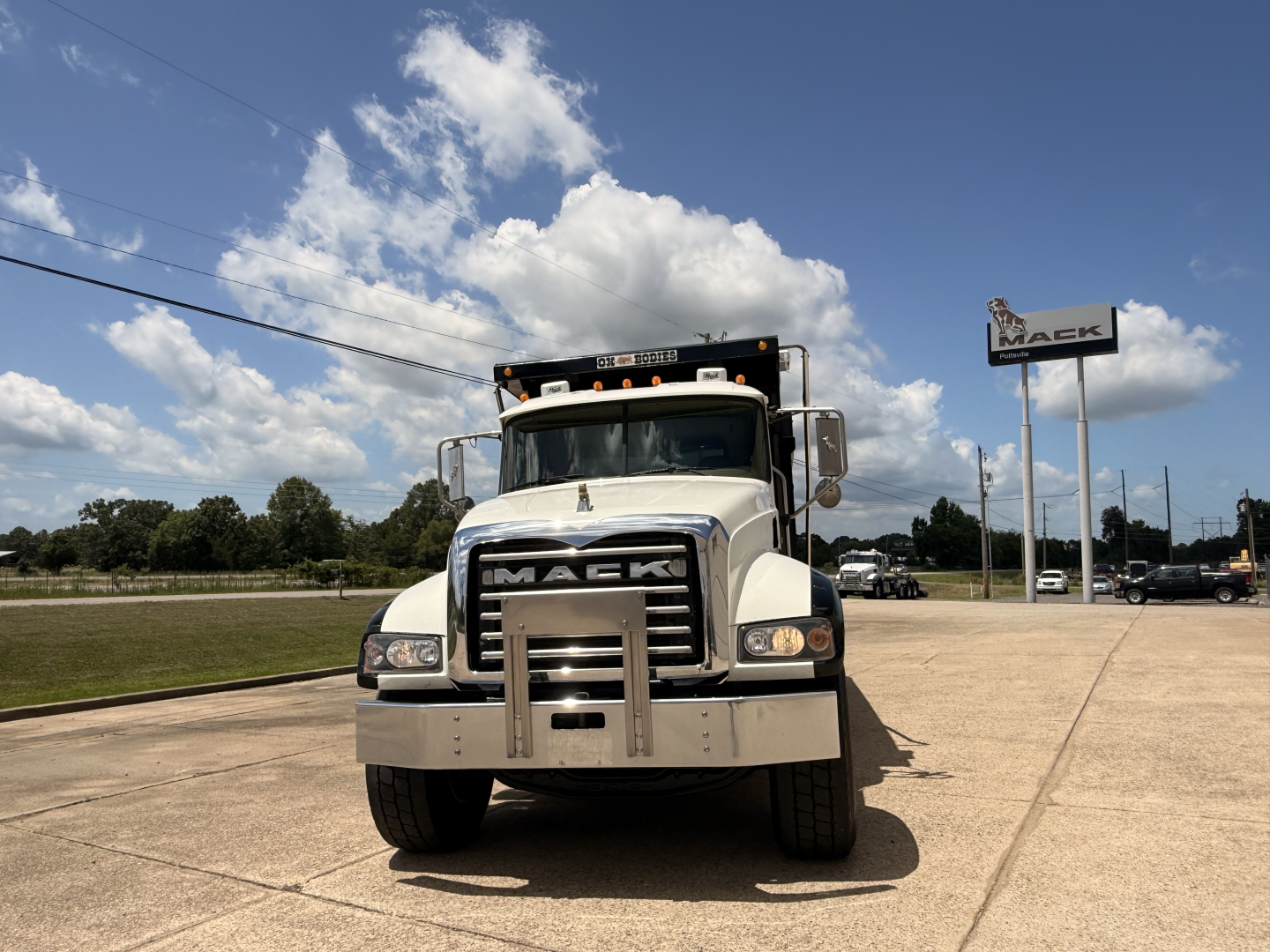 Front view of a white 2016 Mack GU713 dump truck with large grille, light bar on cab, and bumper guard.