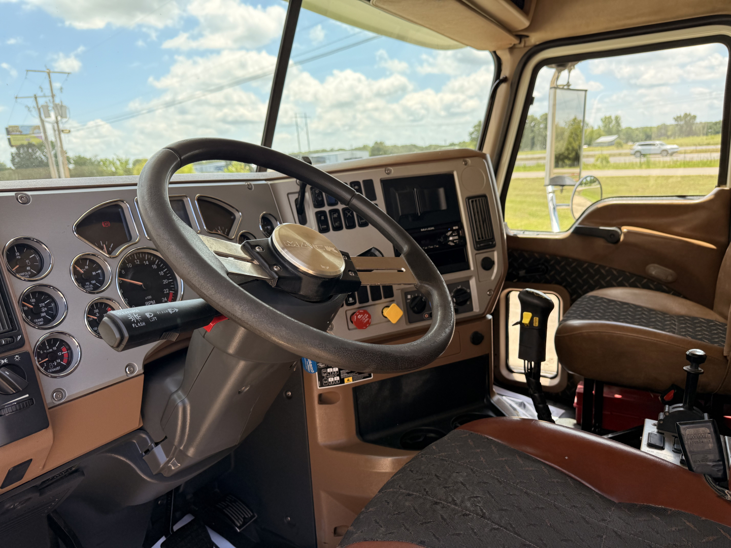 Cab interior of 2016 Mack GU713 dump truck showing steering wheel, instrument cluster, and front passenger seat.