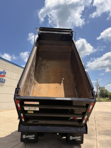 Dump truck bed of a 2016 Mack GU713 dump truck showing empty cargo box and rear tailgate with reflective safety markings.